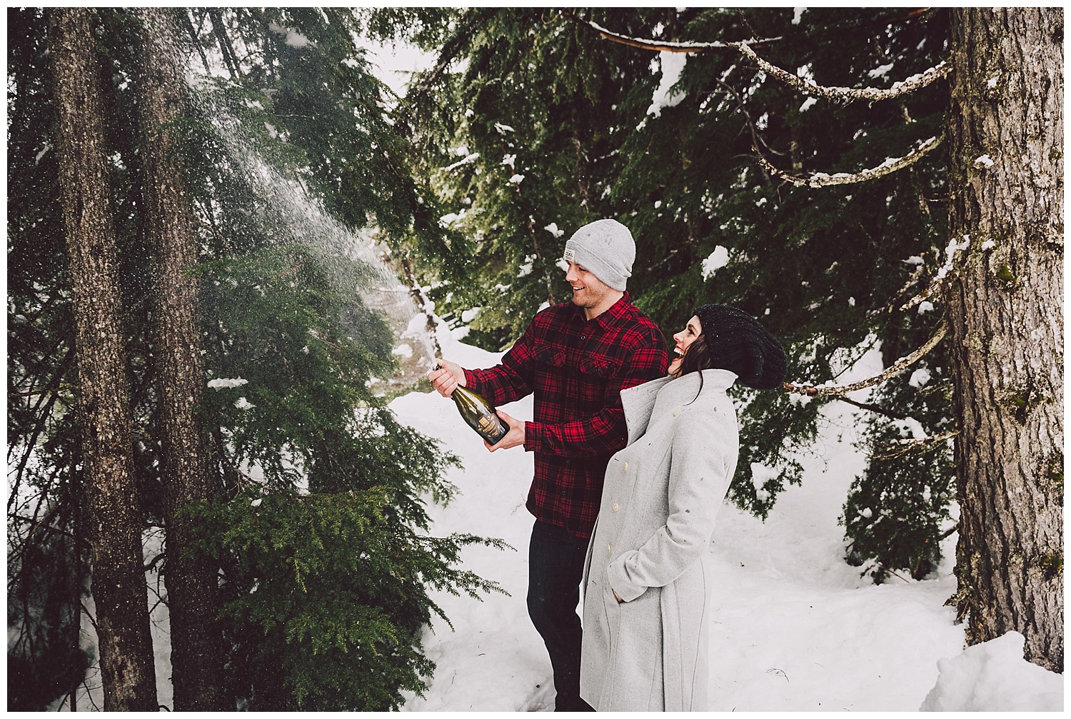 Popping champagne for their snowy engagement photos