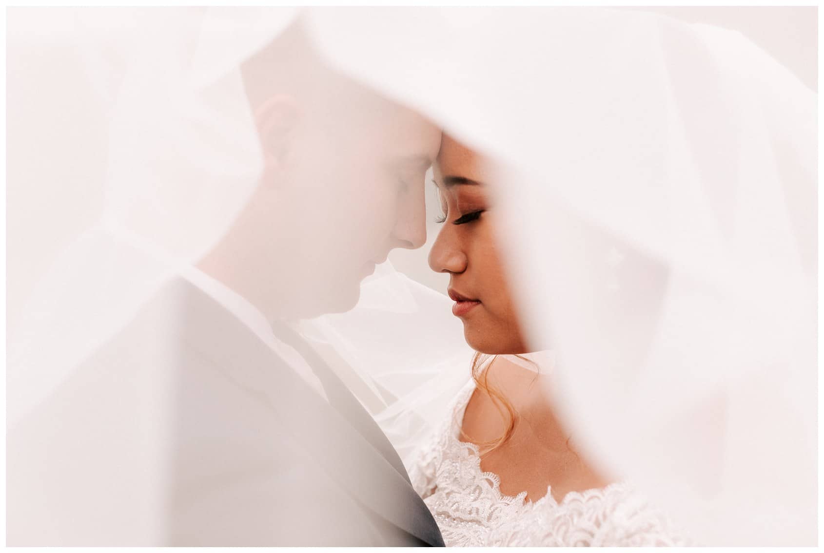 Photo of bride & groom under wedding veil by Seattle wedding photographer Luma Weddings